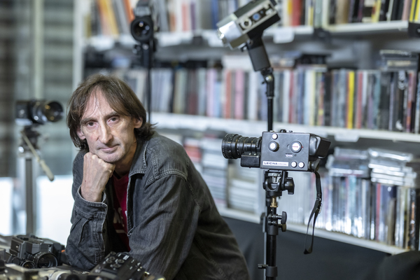 Pip Chodorov assis dans les locaux de Re:Voir &agrave; Paris, entour&eacute; de cam&eacute;ras argentiques et de livres de cin&eacute;ma